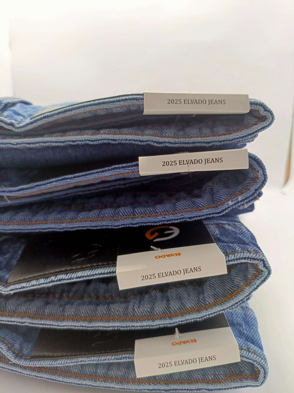Dark indigo acid wash jeans stacked, featuring ELVADO JEANS labels, showcasing slim fit and stretchy cotton design.