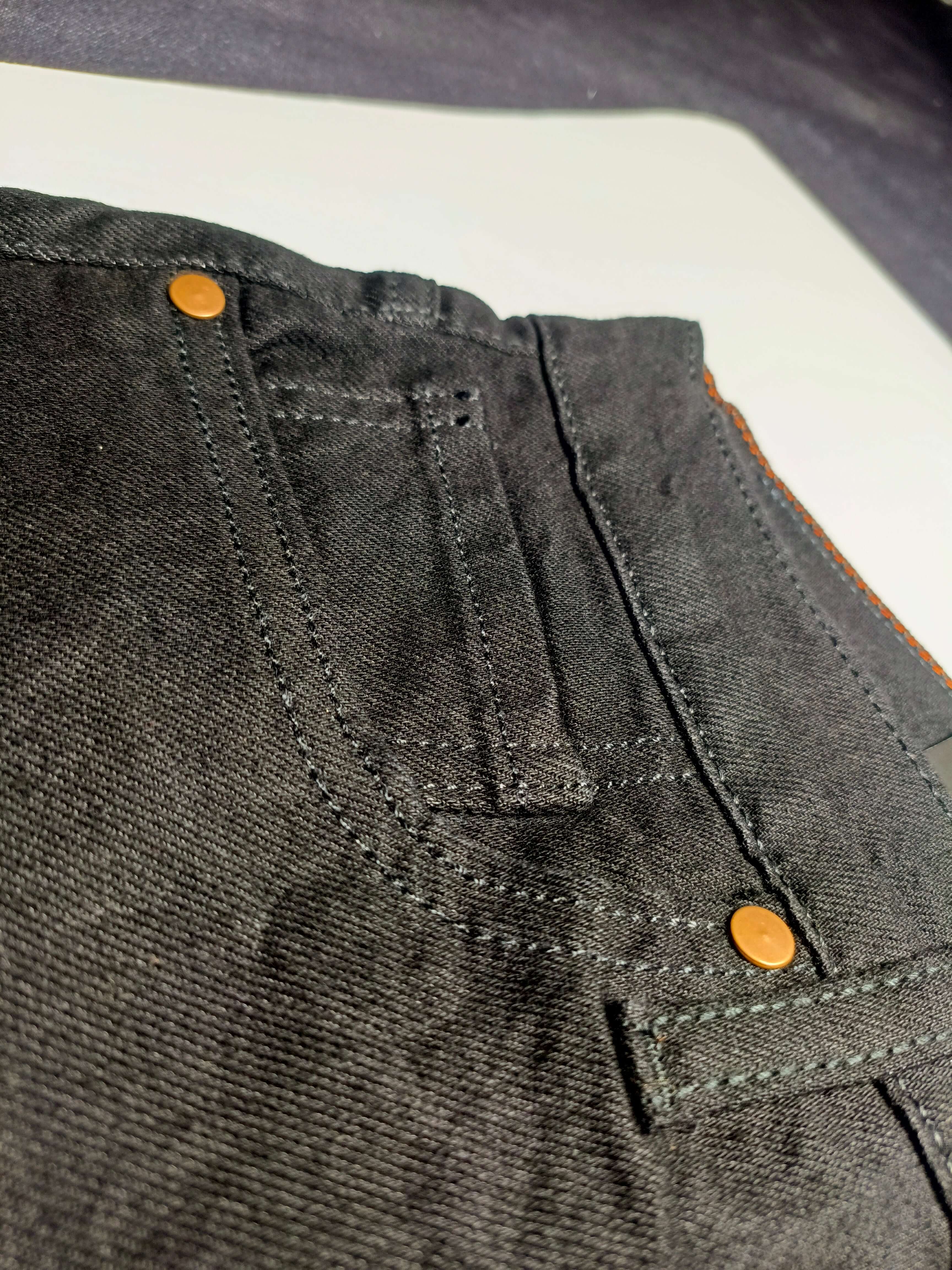 Premium Black Denim close-up of straight fit slim fit jeans detailing with stretchy fabric features.